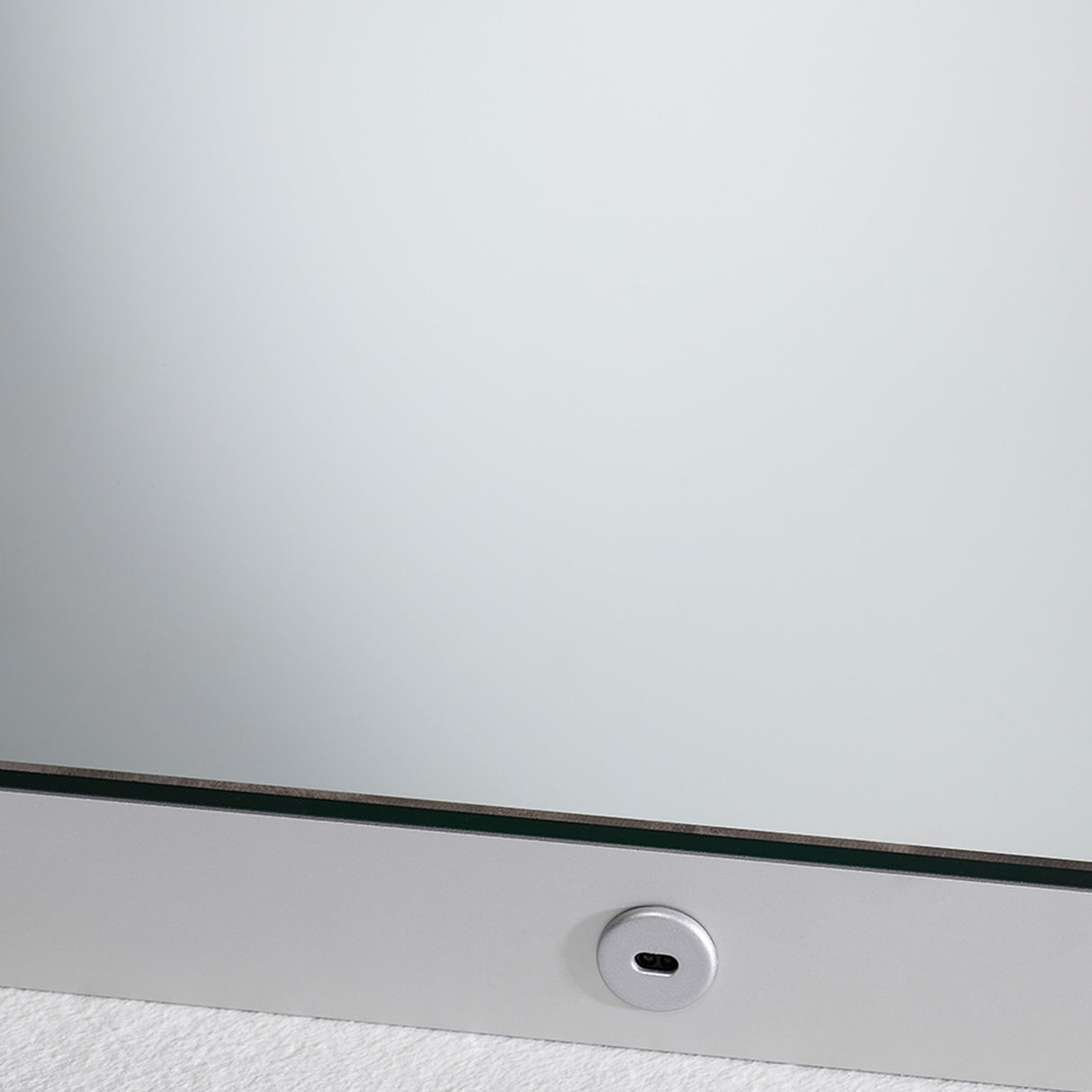 Close-up of the B.Ambi Plus square backlit LED demister bathroom mirror, showing the frameless glass edge and a round touch sensor set into the lower metal frame.