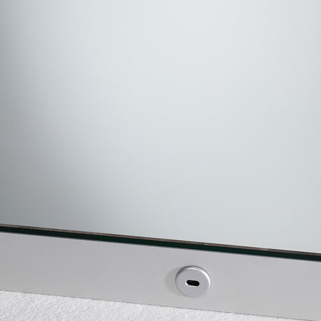 Close-up of the B.Ambi Plus square backlit LED demister bathroom mirror, showing the frameless glass edge and a round touch sensor set into the lower metal frame.
