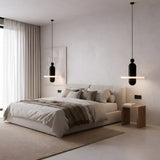 Minimalist bedroom with a low cushioned bed, neutral bedding, Nyxara LED Large Tiered Alabaster Single Pendant Light in soft white & black, wooden nightstand, large window with sheer curtains, beige rug, and abstract wall art on a textured white wall.