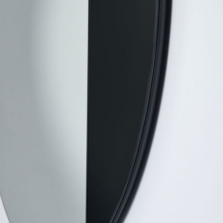 Close-up of the Cord Black Half Tinted Round Wall Mirror 58cm, showing the black frame edge and split between dark tinted glass and clear mirror against a pale wall.