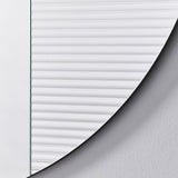 Close-up of the Cord Flutes round wall mirror's edge, showing fine horizontal reeded glass ribbing meeting the curved frameless border, set against a plain light background.