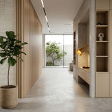 Minimalist hallway with light wood paneling, built-in shelves, a Funk Table Lamp - Brass adding a pop of yellow, potted plant on the left, and a large window at the end revealing a small tree and concrete walls outside.