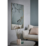 Rectangular wall mirror with gold frame, marble-effect black and bronze veining on the glass, hung in a living room above a beige sofa with cushions.