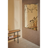 Rectangular wall mirror with gold frame in a hallway, glass surface printed with black marble veining, mounted above a wooden console table.