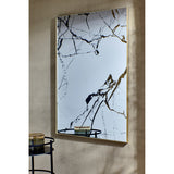Rectangular wall mirror with slim gold frame, featuring black and bronze marble-effect veining printed on the glass, shown in a room setting above a small side table.
