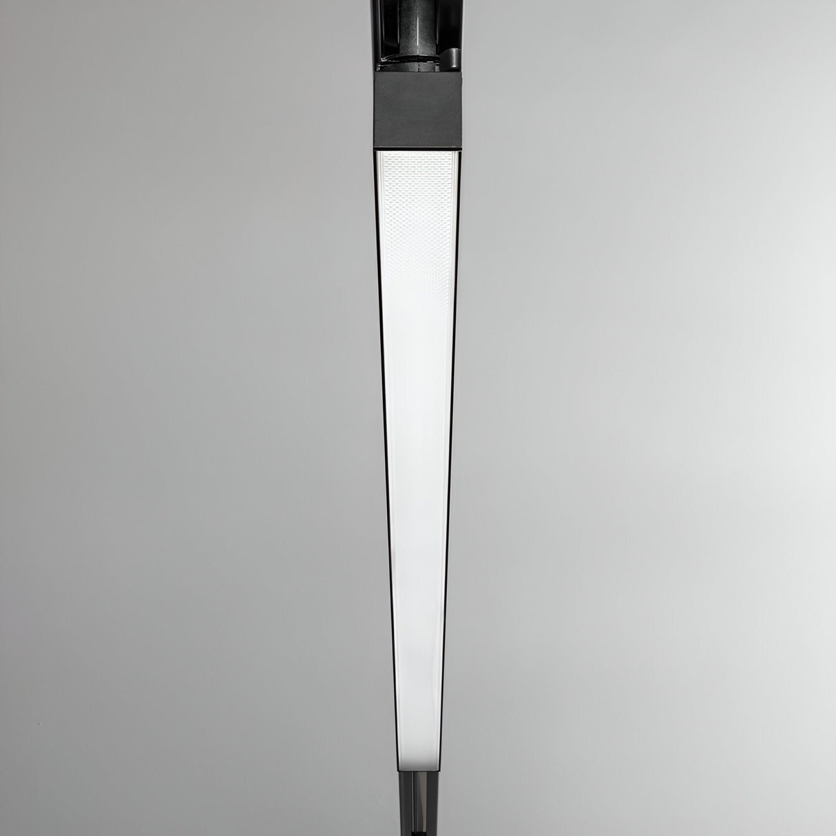 Close-up of the Dune UGR 3-Phase LED Linear Track Light, featuring a modern, minimalist design with a triangular shape and frosted glass diffuser, mounted against a plain gray background. Its sleek lines and monochromatic black color seamlessly integrate into any 3-Phase Track System.