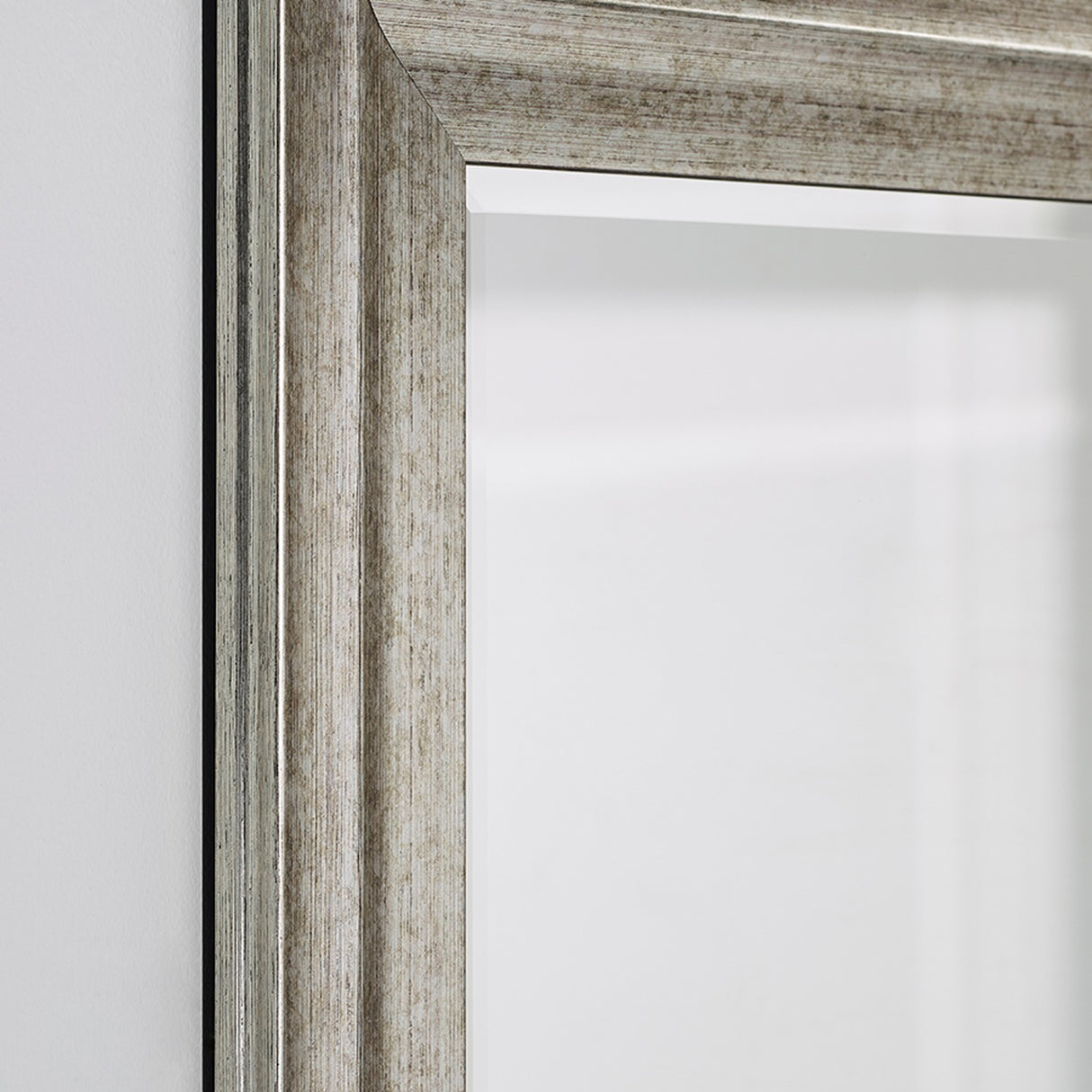Close-up of the Metz full length mirror's corner, showing a stepped, moulded frame in a broken silver finish with a darker ground visible in the grooves.