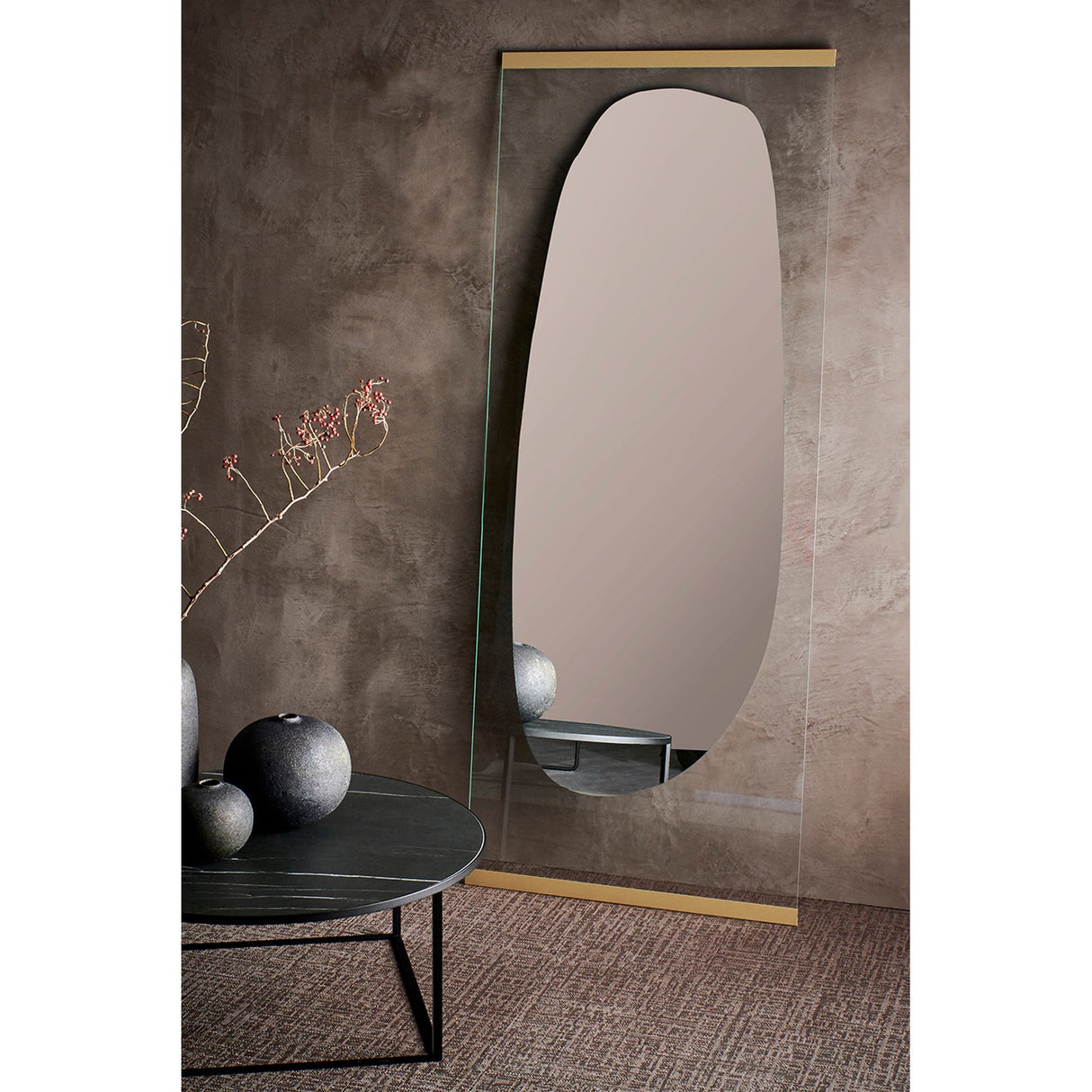Obu Organic Full Length Leaning Mirror 178cm in Gold, with an organic rock-shaped silvered area on a clear glass rectangle, leaning against a wall in a styled room with a side table and vases.