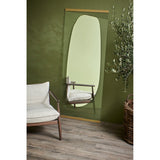 Obu Organic Full Length Leaning Mirror 178cm in Gold, with an organic rock-shaped reflective area set within clear glass, shown leaning against an olive green wall beside an armchair.