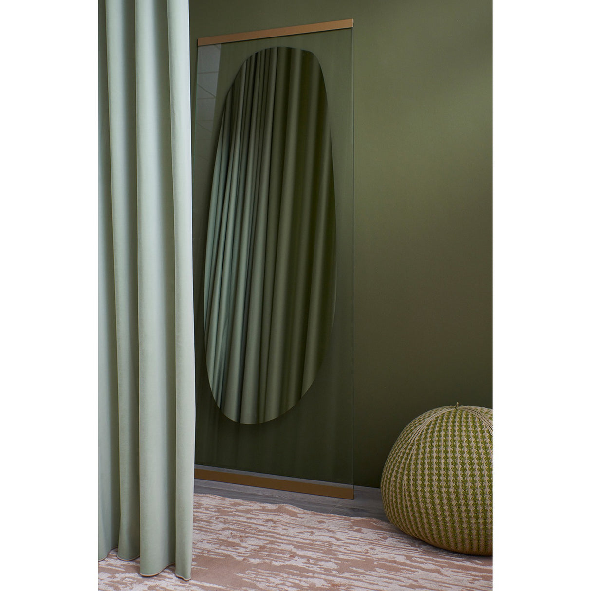 Obu Organic Full Length Leaning Mirror 178cm in gold, with an organic rock-shaped reflective area on clear glass, leaning against an olive green wall beside a sage curtain.