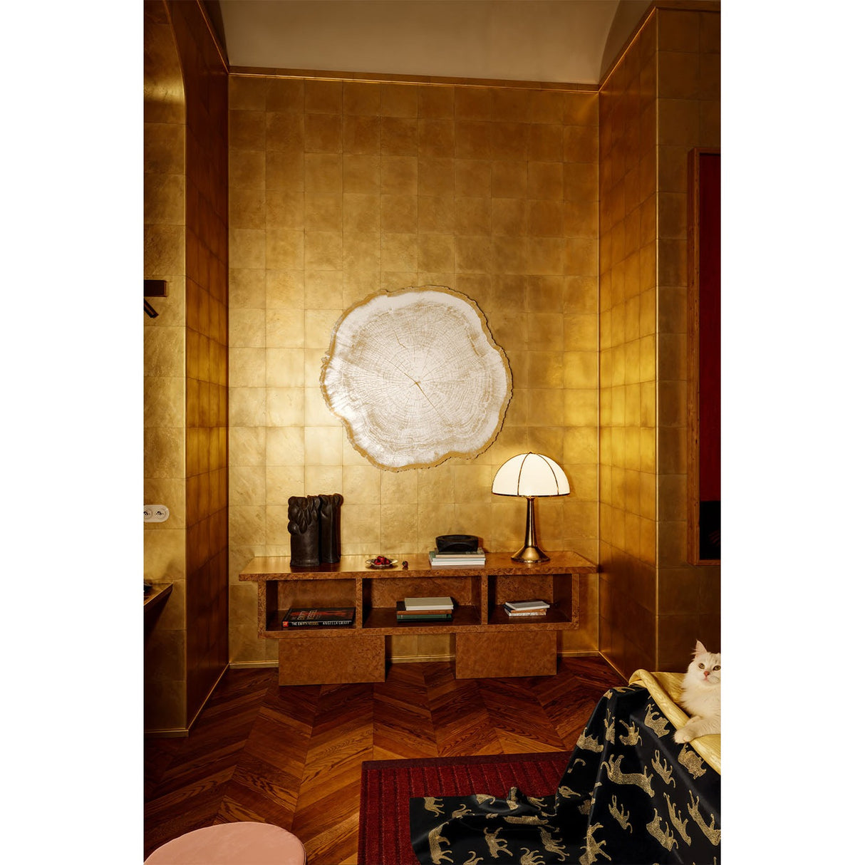Arbo Gold Tree Ring Printed Glass Wall Mirror 80cm, frameless with a gold sawn-edge outline, mounted on a gilded wall above a wood console in a living room setting.