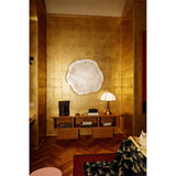 Arbo Gold Tree Ring Printed Glass Wall Mirror 80cm, frameless with a gold sawn-edge outline, mounted on a gilded wall above a wood console in a living room setting.