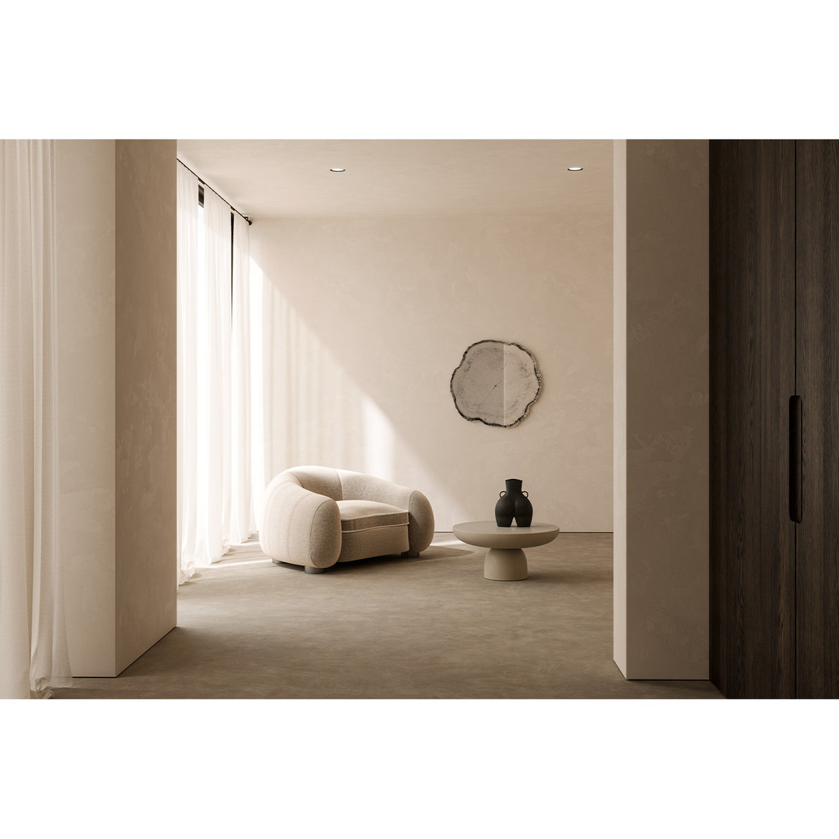 Arbo Dark Tree Ring Printed Glass Wall Mirror 80cm with an irregular frameless outline and charcoal bark-like edge, hung in a neutral hallway above a boucle armchair and coffee table.