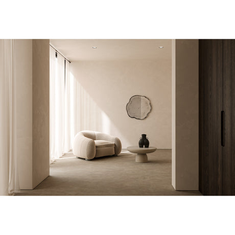 Arbo Dark Tree Ring Printed Glass Wall Mirror 80cm with an irregular frameless outline and charcoal bark-like edge, hung in a neutral hallway above a boucle armchair and coffee table.
