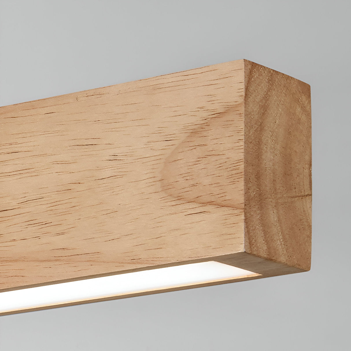 A detailed view of the Erin LED Wood Wall Light 13W, featuring a minimalist design in light brown. The natural wood texture emits a gentle white glow with its 3000K illumination from the bottom. This modern wall light is striking against a simple, light gray backdrop, measuring 60cm in length.