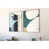 Mika Blue Printed Glass Wall Mirror in a slim black metal frame, shown beside a matching mirror on a wall, with abstract teal, white and sandy curved shapes printed across the lower glass.