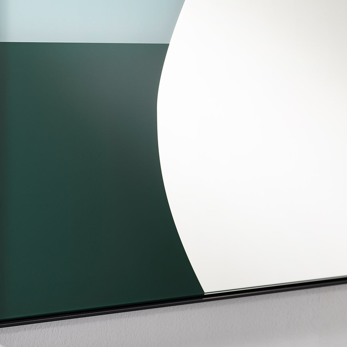 Mika Blue printed glass wall mirror in a slim black metal frame, close-up of curved teal and green shapes on the lower reflective surface.
