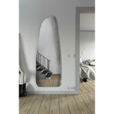 Rocca Standing Stone Printed Glass Wall Mirror 175cm, a frameless irregular mirror shaped like a menhir with a screen-printed stone pattern, mounted in a hallway near a staircase.