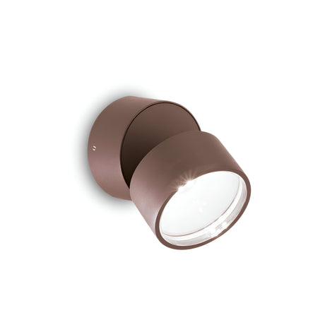 The Arcane Round Outdoor LED Single Spotlight 7W 4000K - Brown is a contemporary cylindrical wall light fixture with a matte finish and a transparent front for the bulb. It mounts on a circular base and is suitable for both indoor and outdoor use with an IP54 rating, providing optimal brightness with its 4000K LED light.
