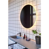 Brio Clear Round LED IP44 Bathroom Mirror, frameless round mirror with backlit LED glow, mounted above a bathroom vanity with black tap and tiled wall.