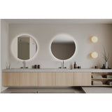 Brio Clear Round LED IP44 Bathroom Mirror, frameless backlit round mirror above a floating wood vanity, shown alongside a second round mirror and globe wall lights.