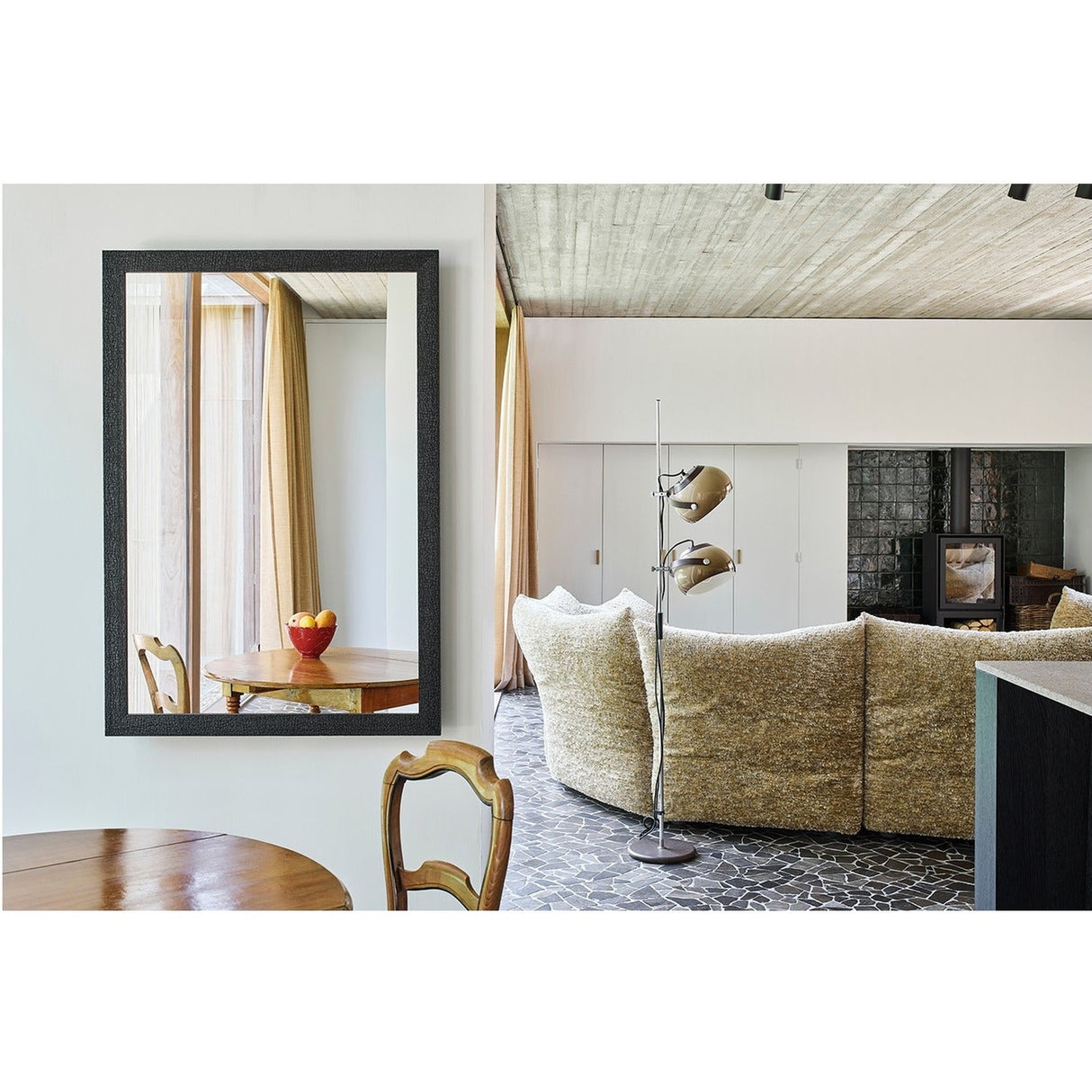 Kyo Charred Wood Rectangular Wall Mirror in black, textured wooden frame, reflecting a dining table and living room with sofa and floor lamp.