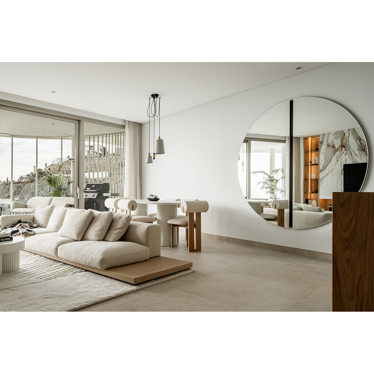 Round black-framed wall mirror by Luna, 200cm, mounted in a living room, showing a recessed black glass strip at its central joint reflecting the space.