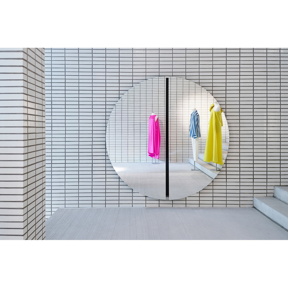 Luna Black Two Piece Round Wall Mirror 200cm, a large frameless round mirror in two halves with a black lacquered glass strip at the centre join, shown on a white tiled wall.