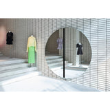 Luna Black Two Piece Round Wall Mirror 200cm mounted on tiled wall in a boutique setting, frameless glass split by a central black lacquered strip, reflecting displayed garments.