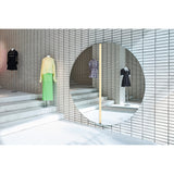 Luna Light LED Two Piece Round Wall Mirror 200cm, a large frameless round mirror with a central LED strip, mounted on a tiled wall reflecting displayed garments in a showroom.