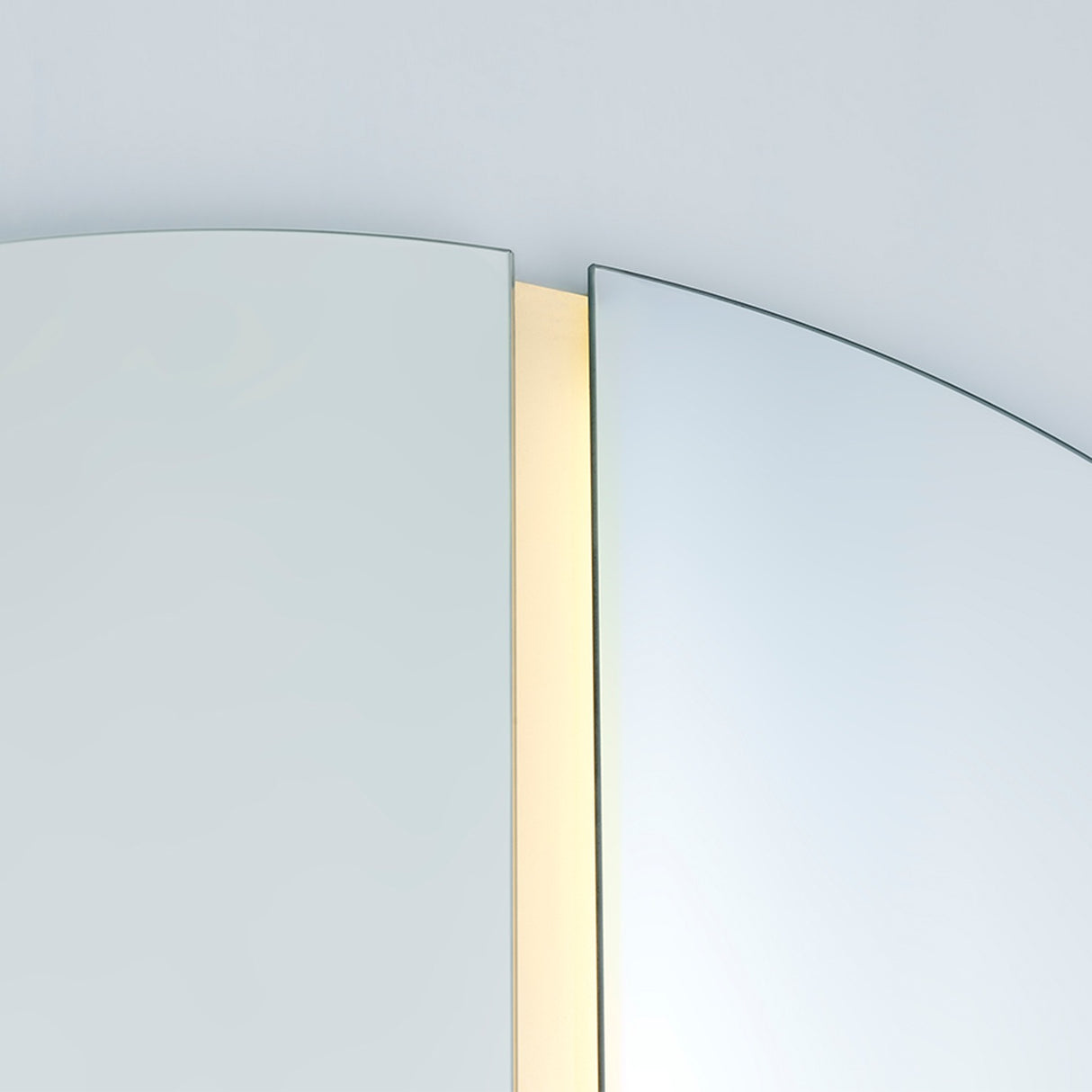 Close-up of the lit joint, the warm LED strip set deep into the channel between the two half moons.