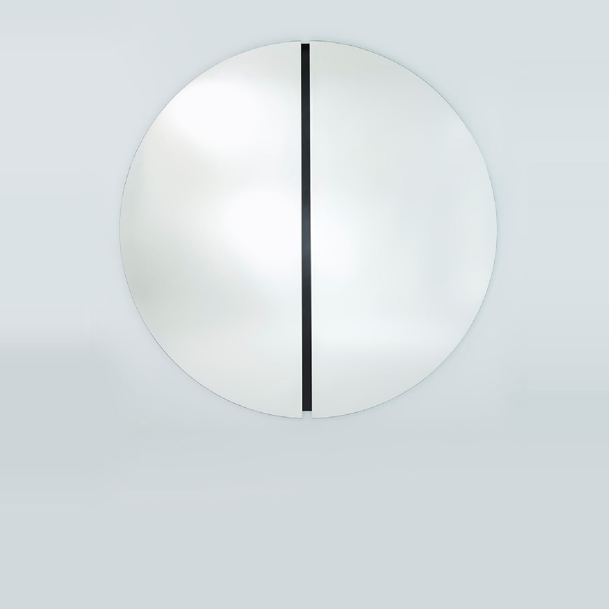 The two metre round mirror seen straight on, the black glass strip running the full height of the recessed central joint.
