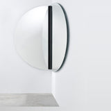 Luna Black Two Piece Corner Wall Mirror 150cm, a round frameless glass mirror split into two halves mounted at a corner angle, joined by a black lacquered strip.