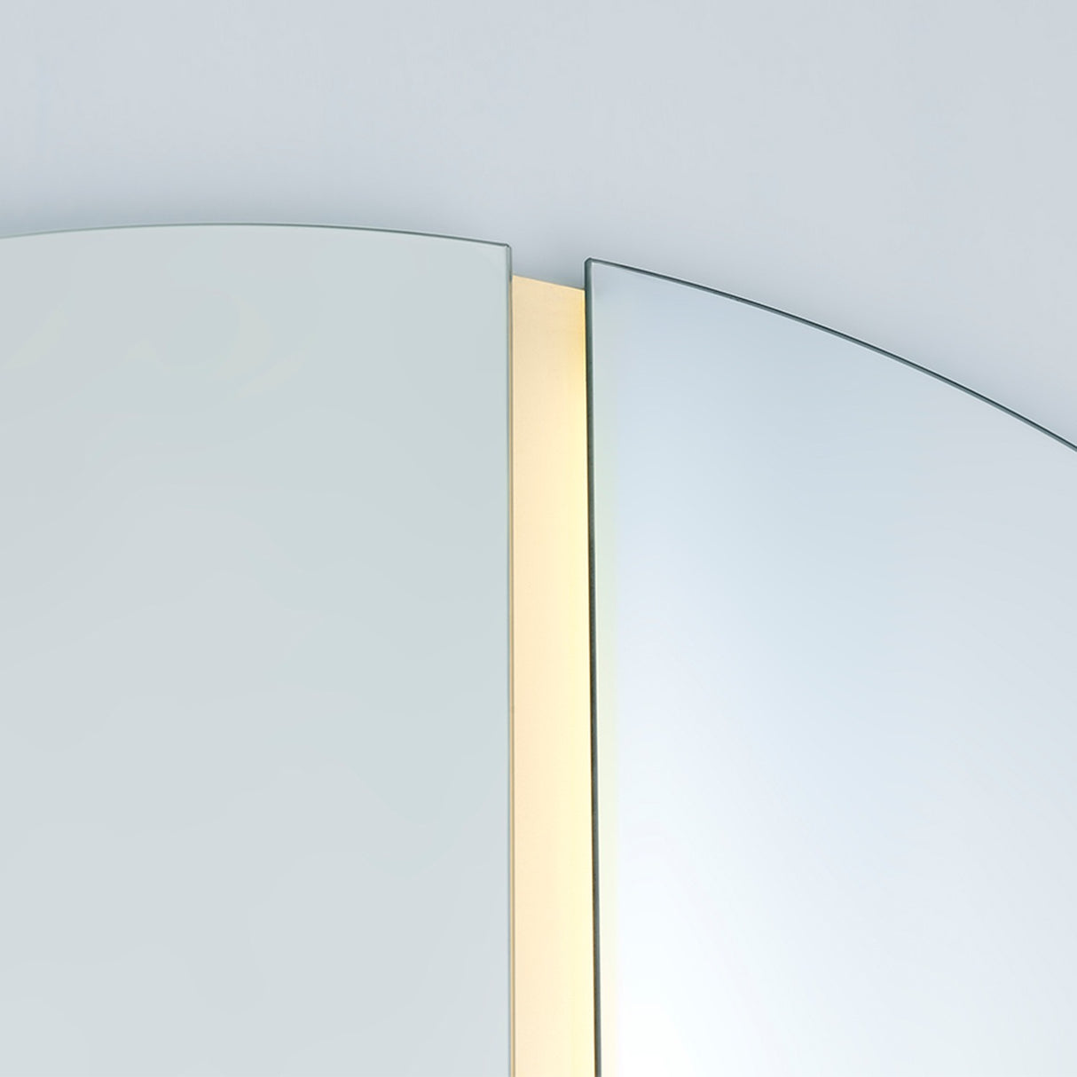 Close-up of the Luna Light LED Two Piece Square Wall Mirror, showing frameless glass panes with a vertical LED strip glowing between them against a light background.