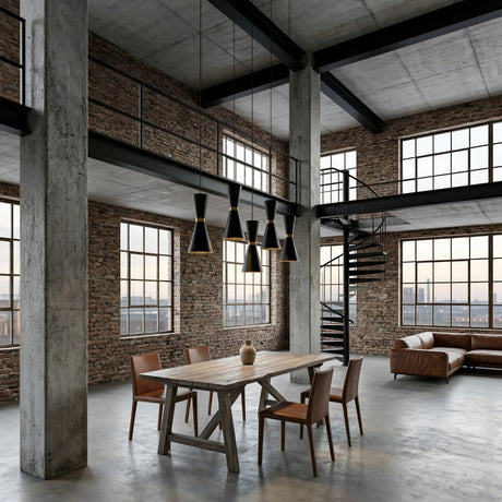 Spacious industrial loft with large windows, exposed brick walls, concrete floors, a wooden dining table and four chairs, a brown leather sectional sofa, a spiral staircase, and Ramses Pendant Light - Black hanging overhead.