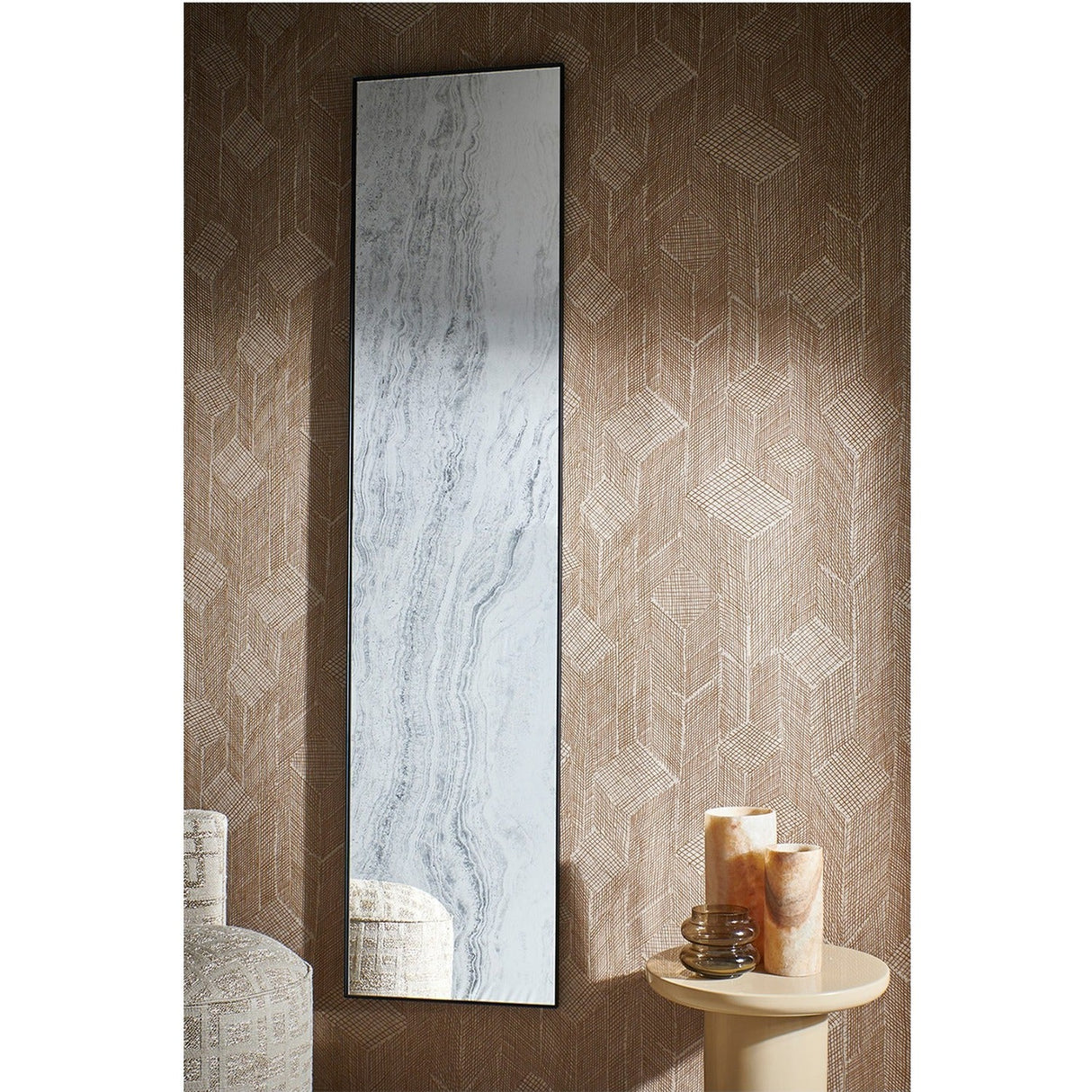 Travertin rectangular wall mirror with thin black metal frame and travertine-print glass, mounted on textured brown wallpaper beside a side table with candles.