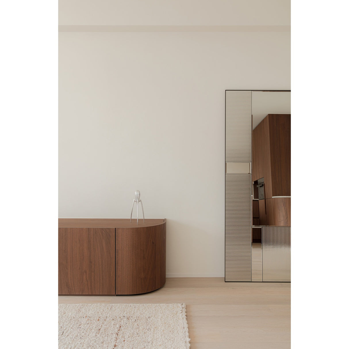 Finestra Flutes full length mirror in a black metal frame, combining fluted textured glass and plain mirror panels, shown against a wall beside a walnut sideboard.