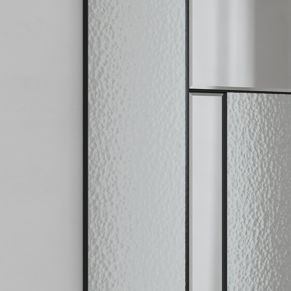 Close-up of the Finestra Deco full length mirror in black, showing slim metal grid bars framing reeded textured glass panels against a plain light grey wall.