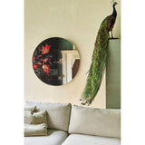 Museo Still Life Printed Round Wall Mirror 100cm, frameless glass with dark floral still-life print, hung above a beige sofa beside a taxidermy peacock display.