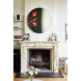 Museo Still Life Printed Round Wall Mirror 100cm, frameless glass mirror with a printed floral still-life fragment on one side, mounted above a marble fireplace in a living room.