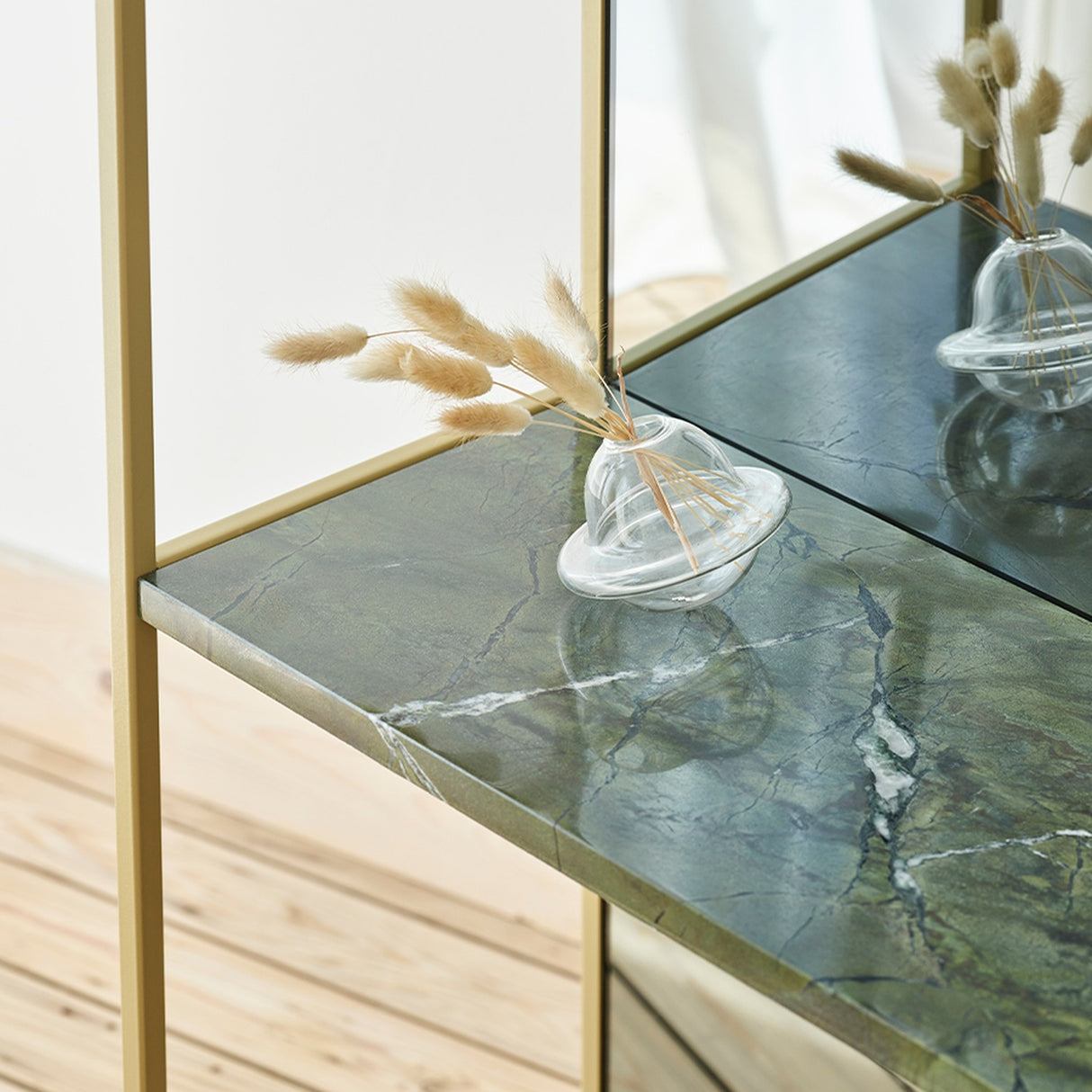 Chassis XL Deluxe free standing mirror detail showing gold metal frame and green marble shelf with a glass bud vase and dried pampas grass stems.