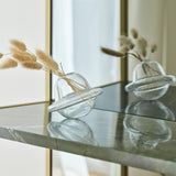 Close-up of the Chassis XL Deluxe free standing mirror's green marble shelf with gold metal frame, holding a clear glass vase with dried grass, reflected in the mirror.