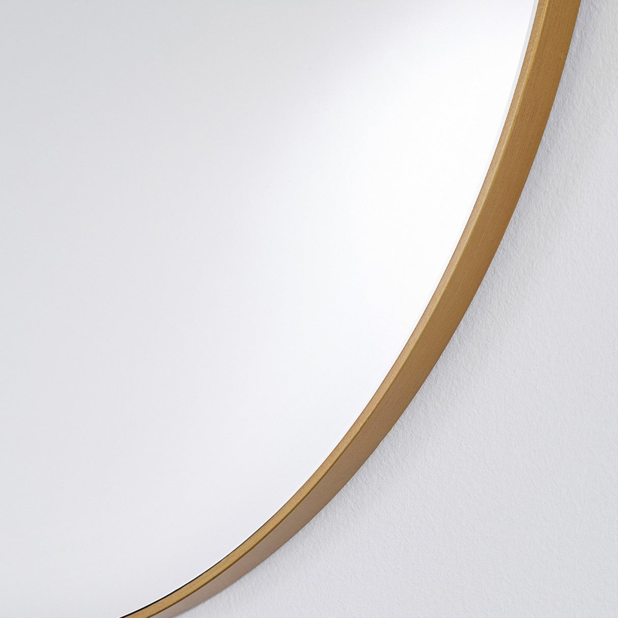 Close-up of the Hoop Bronze Round Wall Mirror 105cm, showing the thin bronze metal rim against the mirrored glass edge, set on a plain white wall.