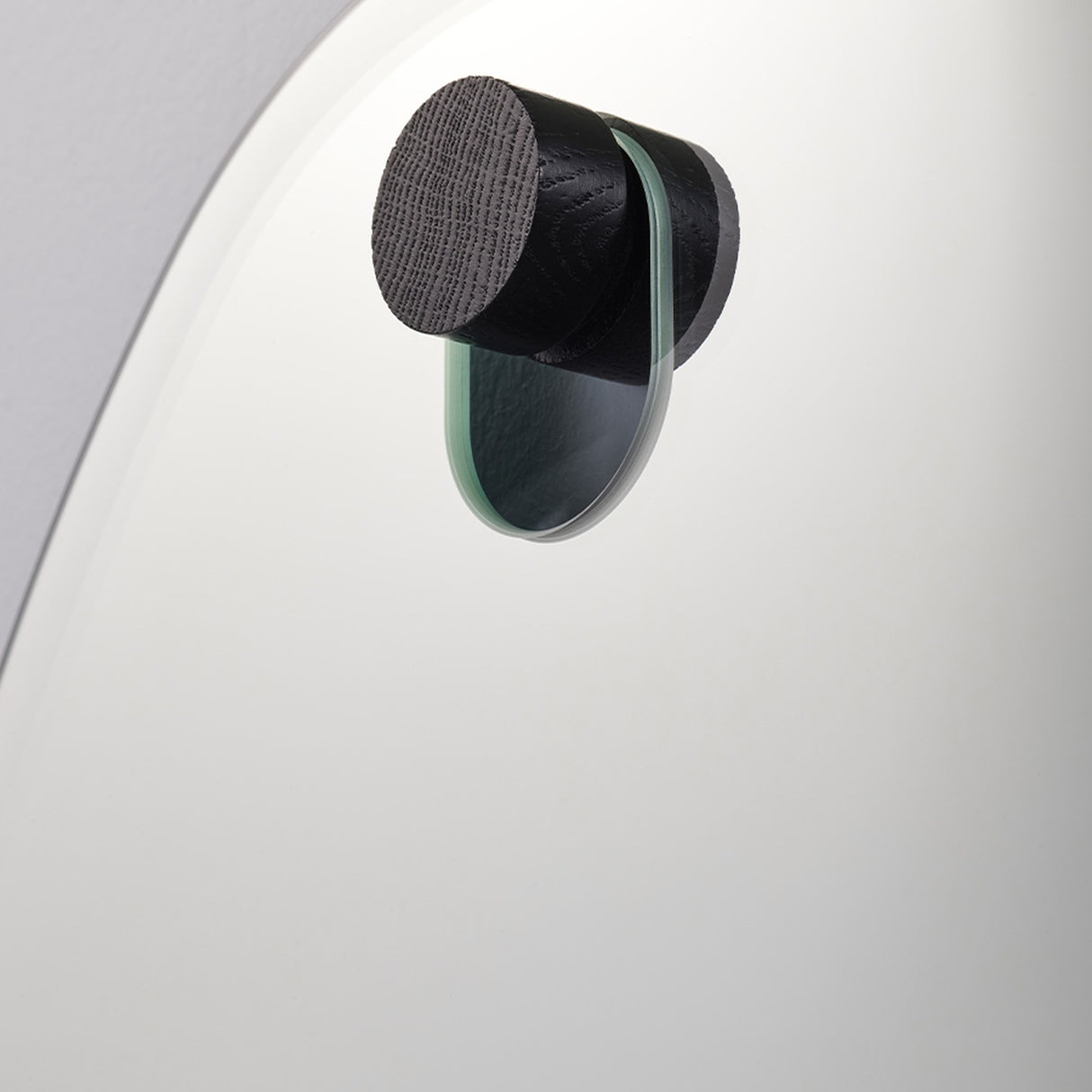 Close-up of the black oak peg passing through the glass, with the green edge of the pane visible.