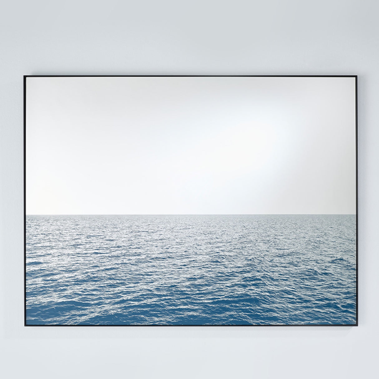 Maro Seascape Printed Glass Wall Mirror 120cm, rectangular black-framed mirror with a printed blue seascape below the horizon and a mirrored sky above, on a plain light grey wall.