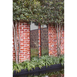 Lucka Outdoor Full Length Garden Mirror 175cm in black, slim metal frame mounted on a red brick garden wall amid trees, grasses and a reflecting pool.
