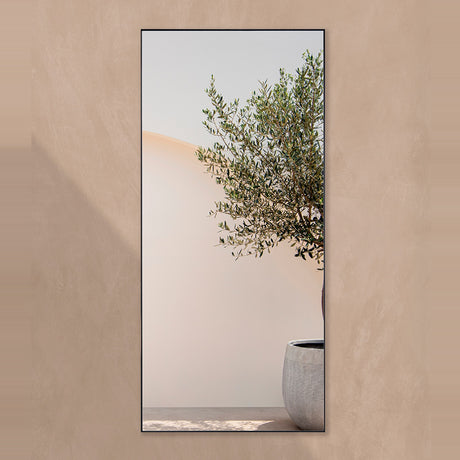 Lucka Outdoor XL full length garden mirror, 175cm rectangular design with slim black metal frame, mounted on a beige wall reflecting an olive tree and stone planter.