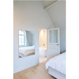 Lucka Solid Oak Full Length Mirror in a bedroom, rectangular wall mirror with slim oak frame reflecting a bed and arched window.