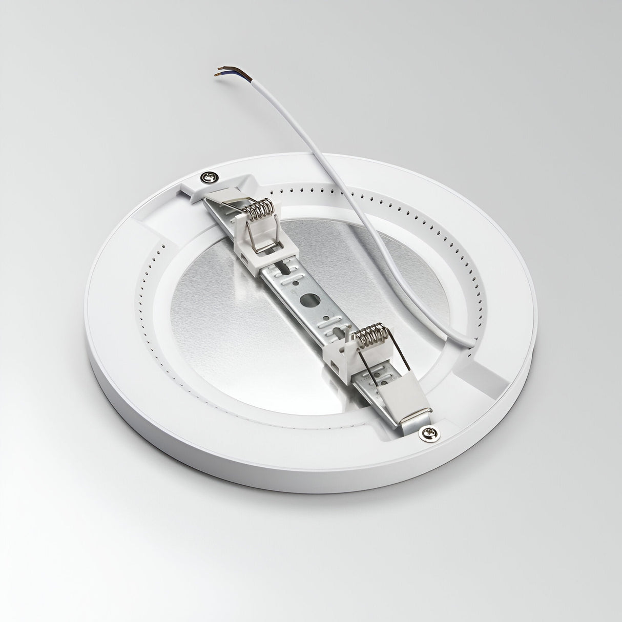 The Lucella Recessed Round LED Downlight is a 20W, 3000K white fixture featuring a flat design with a metallic center and two spring-loaded clips for easy mounting. An energy-efficient option, it has an electrical wire extending from one side and is showcased against a simple light gray background.
