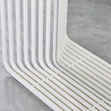 Close-up of the Echo White Double Sided Free Standing Mirror, showing white powder-coated metal slats curving at the base around a mirrored panel, set on a concrete floor.